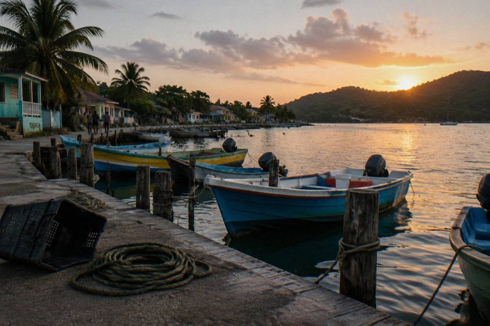 A small boat dock at dusk in a Caribbean fishing village with moored vessels