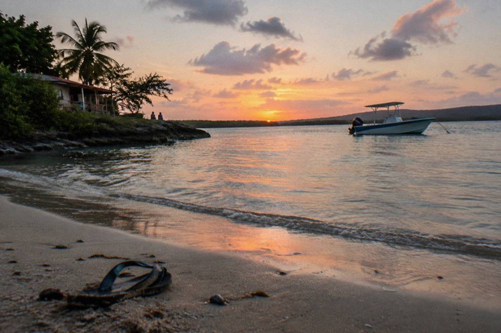 An anchored boat on a sheltered bay at dusk with calm water and scattered clouds