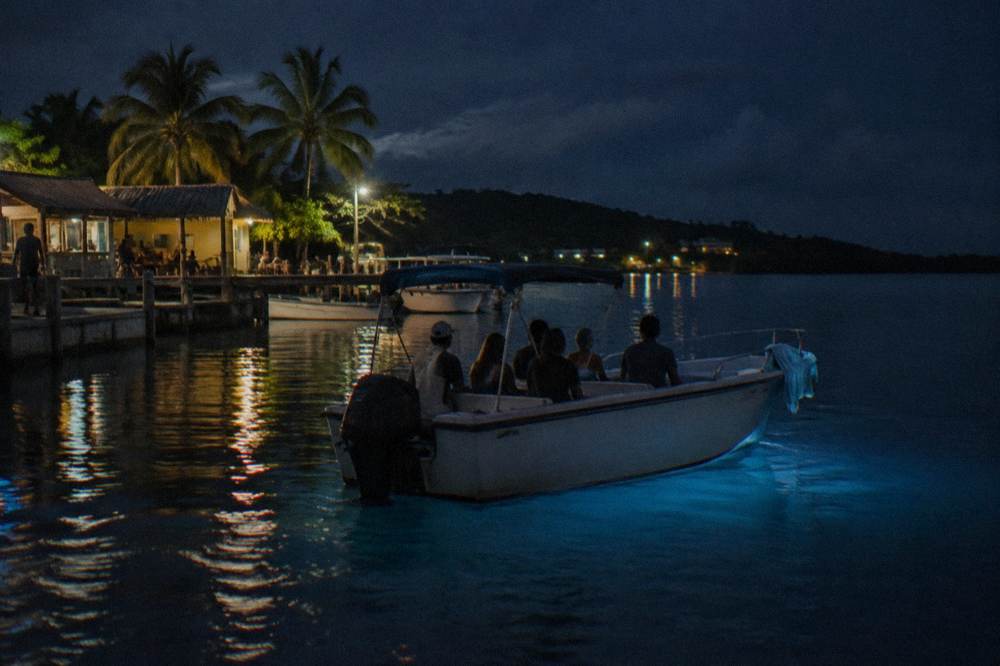 A small boat with passengers drifting on dark still water at night