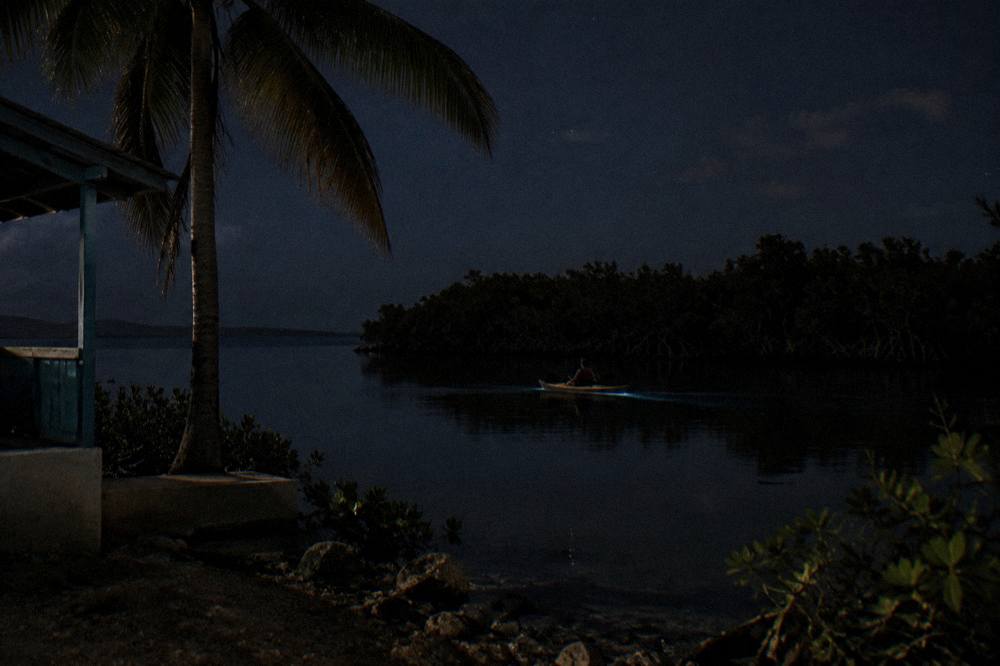 A kayak gliding across dark calm lagoon water at night