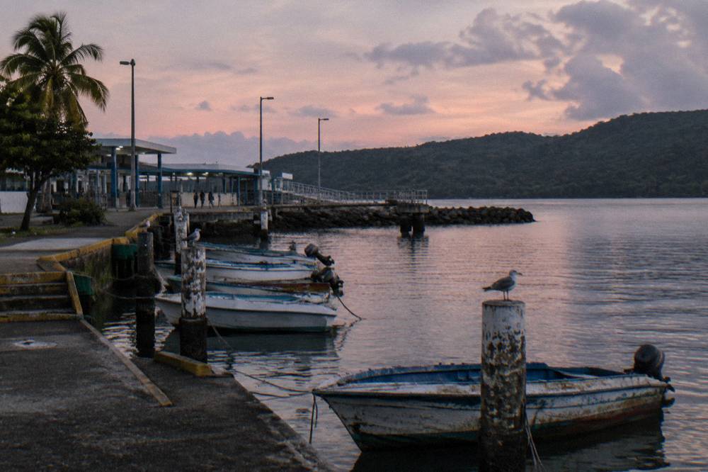 A ferry dock at dusk with calm water and moored small boats