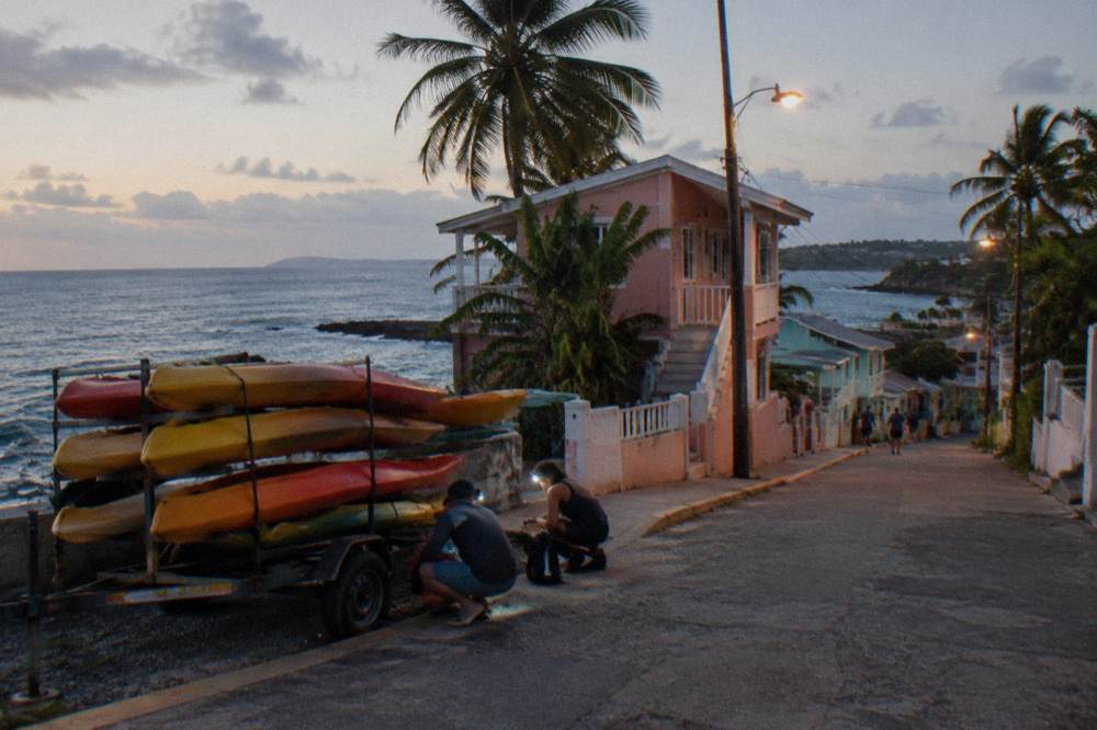 Tandem kayaks lined up on a dark shoreline with guides preparing headlamps before departure