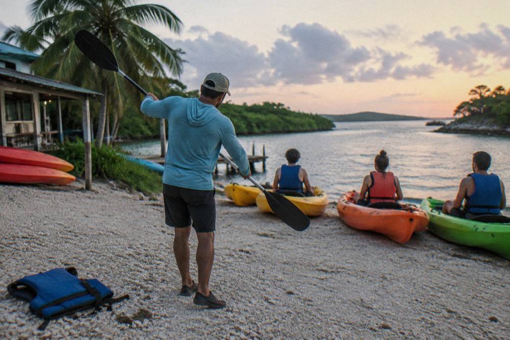 A guide demonstrating paddle strokes to seated guests before a night launch