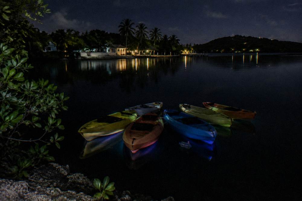 A small cluster of kayaks floating close together on calm black water at night