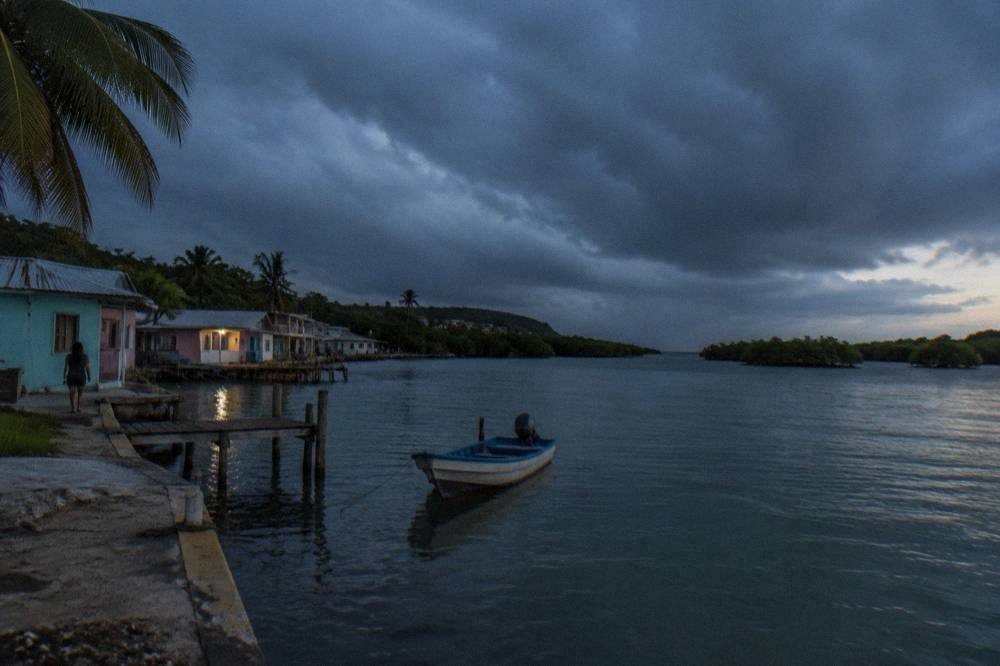 Rain clouds gathering over a calm tropical lagoon at dusk