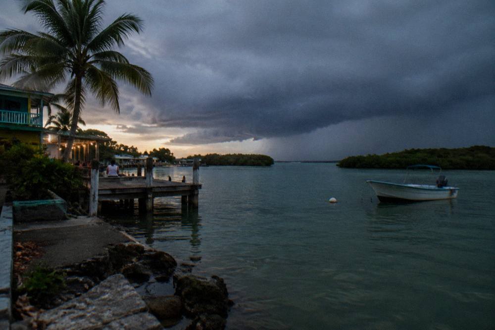 Rain clouds gathering over a calm tropical lagoon at dusk