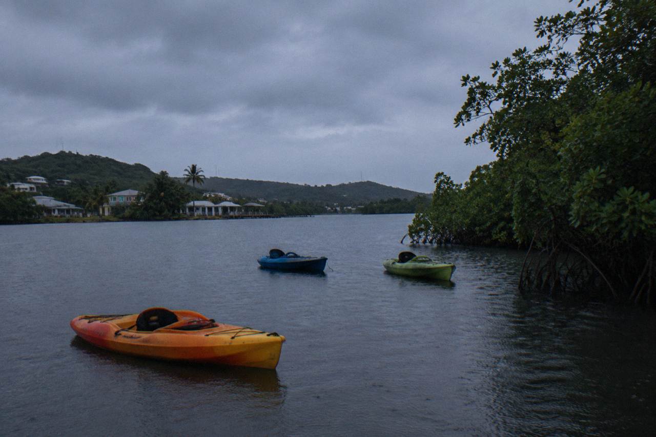 Kayakers waiting on a dark lagoon under an overcast evening sky