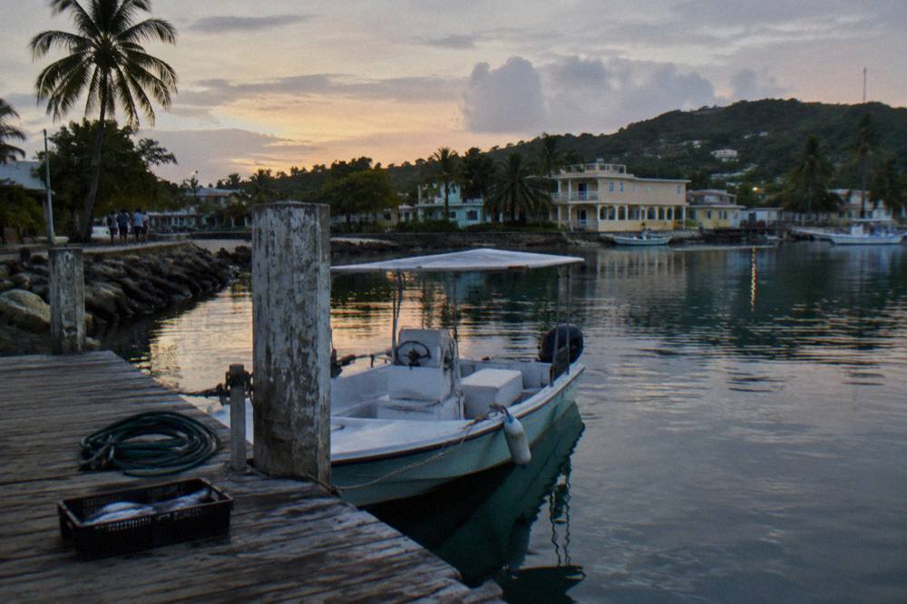 A small electric boat moored at a dock in a fishing village at dusk with calm water