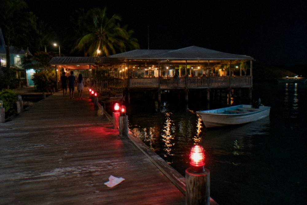 A boarding dock at night with a small boat waiting and soft red lighting along the pier