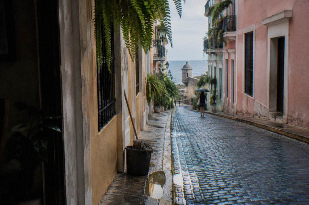 Narrow colonial alley with blue cobblestones and hanging plants in Old San Juan