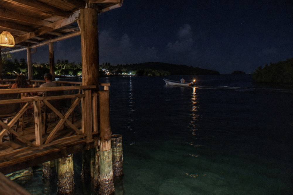 A small open boat crossing dark open water under a starry sky