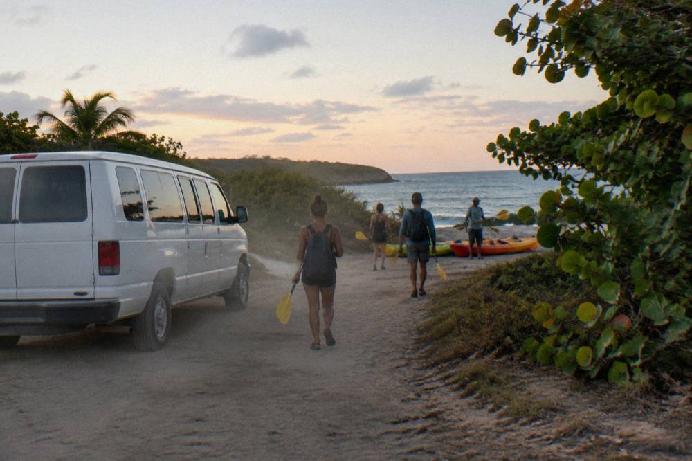 A guide briefing a small group of kayakers on a dark shoreline before launch