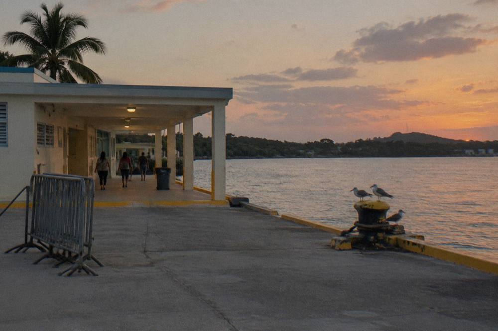 A coastal ferry terminal building beside calm Caribbean water at dusk