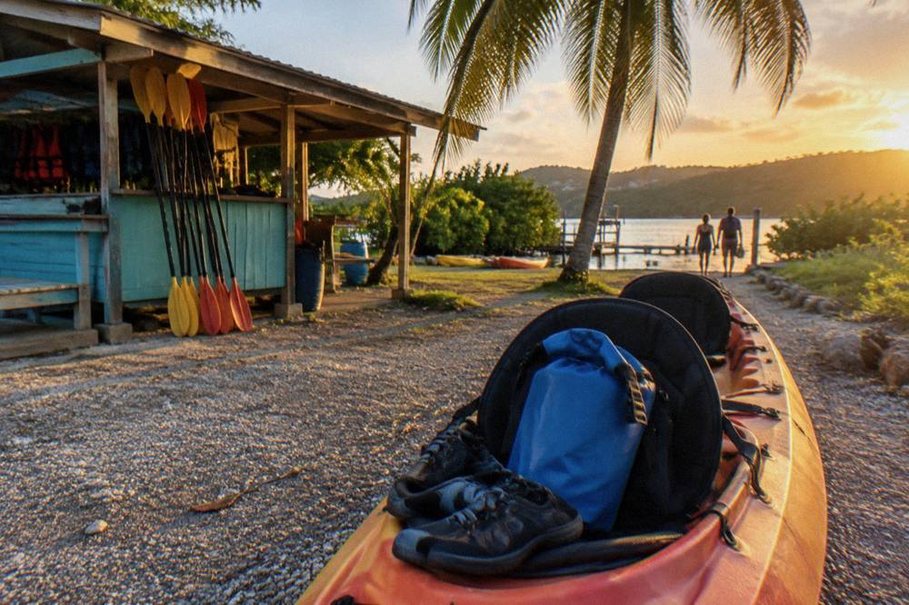 Strapped water shoes and a dry bag resting on a kayak seat before departure
