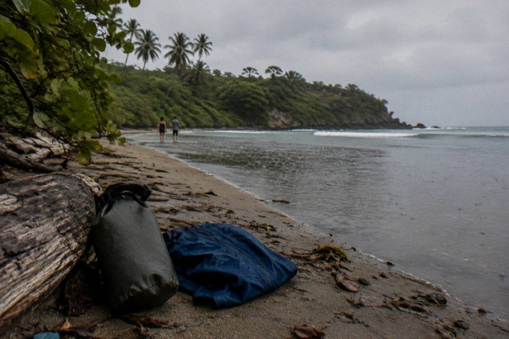 A packable rain shell folded beside a dry bag on a dock at dusk