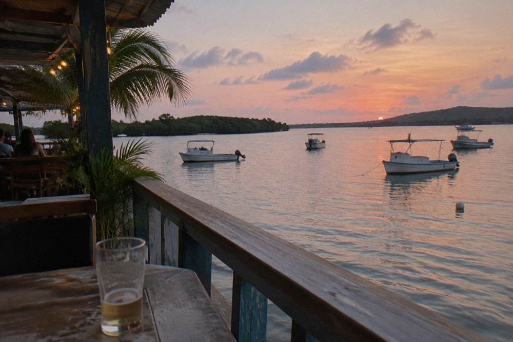 Small fishing boats anchored in a quiet Caribbean cove at dusk with pastel light on the water